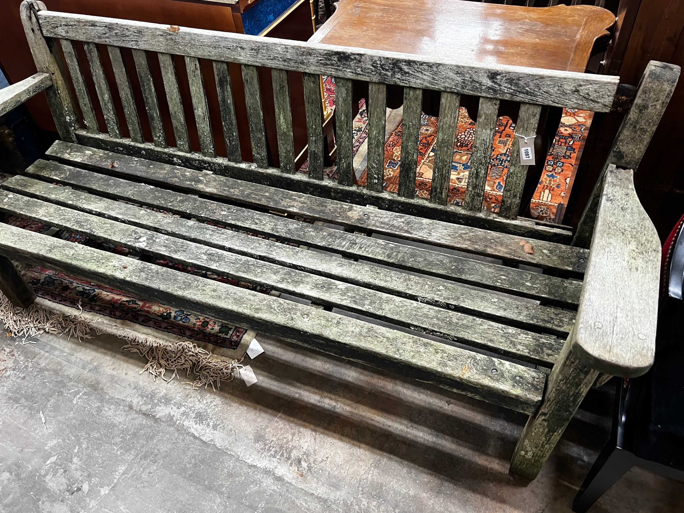 A weathered teak garden bench, length 194cm, height 83cm (a.f.)